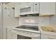 Close-up of kitchen appliances featuring a white range and microwave at 521 Circlewood Dr # Q11, Venice, FL 34293