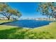 Beautiful water view with lush green lawn and mature trees under a clear blue sky at 521 Circlewood Dr # Q11, Venice, FL 34293