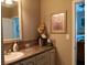 Bathroom vanity featuring a tile countertop, vanity mirror and decoratively framed floral art at 601 Club House Rd, Venice, FL 34285