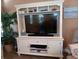 Stylish entertainment center with shelves, cabinets, and a television, complete with a houseplant for a touch of greenery at 601 Club House Rd, Venice, FL 34285