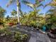 Lush backyard oasis featuring a stone path, vibrant greenery, and tranquil atmosphere under a clear blue sky at 613 Sugarwood Dr, Venice, FL 34292