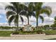 Chestnut Creek community sign surrounded by mature palm trees, landscaping, and a beautiful lake view at 613 Sugarwood Dr, Venice, FL 34292