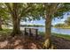 Scenic lake view with a park bench nestled between mature trees, offering a serene and peaceful spot at 613 Sugarwood Dr, Venice, FL 34292