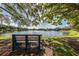 Picturesque lake view featuring a park bench shaded by lush trees on a sunny day, perfect for relaxation at 613 Sugarwood Dr, Venice, FL 34292