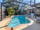 Serene screened-in pool area featuring a waterfall, lush landscaping, and comfortable lounge seating for ultimate relaxation at 613 Sugarwood Dr, Venice, FL 34292