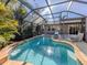 Inviting screened-in pool area with lounge chairs, clear water, and lush tropical landscaping at 613 Sugarwood Dr, Venice, FL 34292