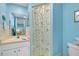 Bathroom with sky blue walls, a white vanity and a shower with a patterned curtain at 616 Circlewood Dr # S2-14, Venice, FL 34293