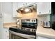Close up of stainless steel stove and oven with white cabinets and tiled backsplash at 616 Circlewood Dr # S2-14, Venice, FL 34293
