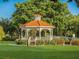 Charming white gazebo with a red tiled roof, surrounded by lush greenery and benches in a serene park setting at 632 Golf Dr # 632, Venice, FL 34285