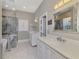 Modern bathroom featuring marble floors, dual vanities, a soaking tub, and a glass-enclosed shower with marble surround at 647 Pond Willow Ln, Venice, FL 34292