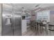 Dining area featuring stainless steel fridge, wood table, and coastal decorations with a modern lighting fixture at 720 Apalachicola Rd # 104, Venice, FL 34285