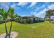 Green backyard with a view of the home's screened in patio and manicured perimeter hedges at 761 Vivienda South Ct # 14, Venice, FL 34293