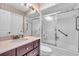 Bathroom with dark wood vanity, framed mirror and a glass-enclosed shower/tub at 761 Vivienda South Ct # 14, Venice, FL 34293