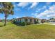 A low-angle view of a single-story home with a well-kept lawn, mature tree, and manicured hedges at 761 Vivienda South Ct # 14, Venice, FL 34293