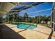 Private pool with screened enclosure, surrounded by a stone patio and lush landscaping at 782 Harrington Lake N Dr # 99, Venice, FL 34293