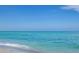 Calm, turquoise water meets the sandy beach under a clear blue sky, offering a serene coastal view at 835 Chalmers Dr # 835, Venice, FL 34293
