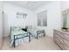 Bright bedroom featuring two twin beds with floral bedding, white walls, and a neutral carpet at 835 Chalmers Dr # 835, Venice, FL 34293