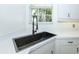 Close up of sink in bright kitchen with white cabinets, modern faucet, view from the kitchen window at 835 Chalmers Dr # 835, Venice, FL 34293