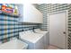 Functional laundry room with a sink, washer, dryer, storage cabinets and plaid wallpaper at 835 Chalmers Dr # 835, Venice, FL 34293