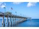 Long pier extending over the water with supports, flag, lights, and a small shop under a bright sky at 835 Chalmers Dr # 835, Venice, FL 34293