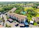 Aerial view of condo complex surrounded by trees, green spaces, covered parking, and a community pool at 838 Bird Bay Way # 114, Venice, FL 34285