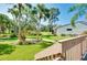 Backyard view from the balcony, showcasing a well-maintained lawn, mature trees, and a sidewalk at 838 Bird Bay Way # 114, Venice, FL 34285