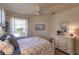 Bright bedroom with a queen bed, fan, white dresser, a cityscape print and windows with sheer curtains at 921 Tartan Dr # 31, Venice, FL 34293