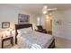 A bedroom featuring a queen bed with floral linens, fan, and a view leading to an adjoining room at 921 Tartan Dr # 31, Venice, FL 34293