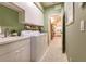 Green laundry room features a sink, laundry machines, white cabinets, decor, and a door at 921 Tartan Dr # 31, Venice, FL 34293