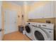 Functional laundry room with white cabinets, washer and dryer, and tile flooring at 9839 Nostalgia Pl, Englewood, FL 34223