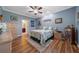 Comfortable bedroom with a ceiling fan, wood floors, en suite bathroom, and serene blue walls at 9839 Nostalgia Pl, Englewood, FL 34223