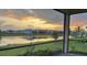 A screened lanai offers sunset views over the lake and lush landscaping at 10399 Abaco Falls Dr, Englewood, FL 34223