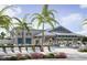 Exterior shot of the community clubhouse with chairs, tables, and palm trees at 10399 Abaco Falls Dr, Englewood, FL 34223
