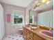 Bathroom featuring patterned wallpaper, pink tile accents, and a wood vanity with double sinks at 1049 N Casey Key Rd, Osprey, FL 34229