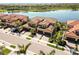 Aerial view featuring townhomes with terracotta tile roofs near a lake and meticulously kept landscaping at 10797 Tarflower Dr # 202, Venice, FL 34293