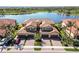 Stunning aerial view of a residential building with a tile roof situated near a serene lake and lush greenery at 10797 Tarflower Dr # 202, Venice, FL 34293