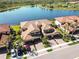 Stunning aerial view of a luxurious townhome community with lake, terracotta tile roofs, and lush landscaping at 10797 Tarflower Dr # 202, Venice, FL 34293