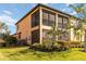 Exterior view of a home featuring a screened balcony, well-maintained lawn, and privacy landscaping at 10797 Tarflower Dr # 202, Venice, FL 34293