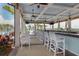 Poolside bar with white stools, ceiling fans, views of the pool and palm trees, creating a relaxing atmosphere at 10797 Tarflower Dr # 202, Venice, FL 34293