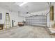 An empty garage with gray concrete flooring, storage rack, and bright lighting at 108 Corte Del Asolo, Venice, FL 34285