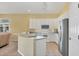 A kitchen with a breakfast bar, white cabinets, stainless steel refrigerator and tile flooring at 108 Corte Del Asolo, Venice, FL 34285