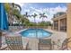Inviting swimming pool with chairs and lush palm trees against a sunny sky at 108 Corte Del Asolo, Venice, FL 34285