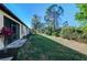 Manicured backyard showcasing a lush lawn, landscaping, and mature trees on a sunny day at 11157 Batello Dr, Venice, FL 34292