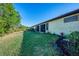 Lush backyard featuring green grass, landscaping, and mature trees behind the house at 11157 Batello Dr, Venice, FL 34292