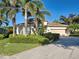 Charming single-story home featuring a manicured lawn, tropical trees, and a two-car garage at 117 Altesino Ct, Venice, FL 34292