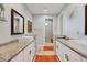 A bathroom featuring double sinks, granite countertops, white cabinetry, mirrors, and eye catching orange rugs at 1207 Henning St, North Port, FL 34288