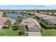 Aerial view of a community home with tile roof, manicured lawn, and serene lake backdrop at 12127 Granite Woods Loop, Venice, FL 34292