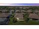 Aerial shot of tile-roofed homes with landscaping in a community around a lake under a vibrant sunset at 12127 Granite Woods Loop, Venice, FL 34292