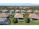 Beautiful aerial view of homes with tile roofs, lush landscaping, and a serene lake in a well-maintained community at 12127 Granite Woods Loop, Venice, FL 34292
