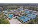 Aerial view of community amenities with a pool, tennis courts, clubhouse, volleyball court, and serene lake at 12127 Granite Woods Loop, Venice, FL 34292